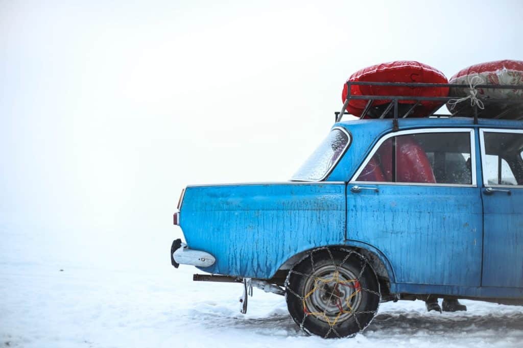 Altes Auto mit Dachgepäck im Winterschnee