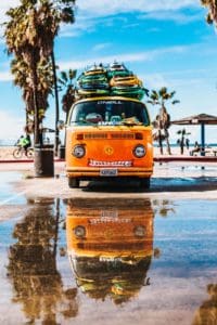 Orangener VW Hippie-Camperbus mit Surfbrettern